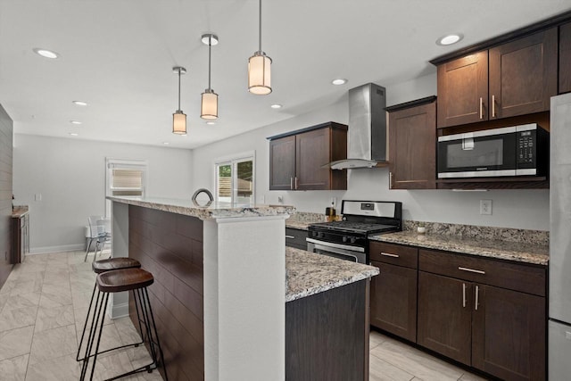 915 E Ohio Ave, Milwaukee, WI 53207 - kitchen featuring appliances with stainless steel finishes, wall chimney range hood, a breakfast bar, a kitchen island with sink, and dark brown cabinetry
