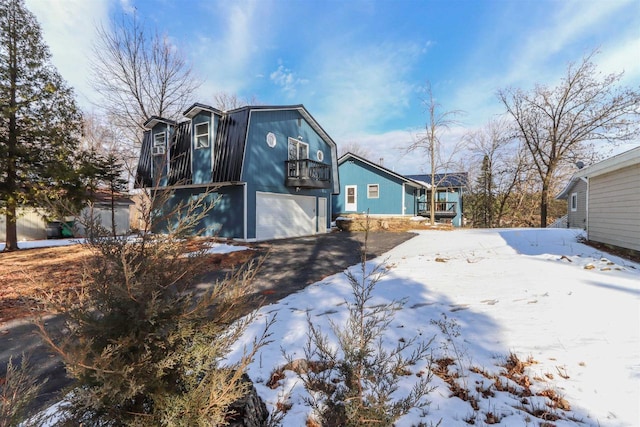 N1416 W Stratton Rd, Waupaca, WI 54981 - view of front facade featuring a gambrel roof, a garage, a balcony, and driveway