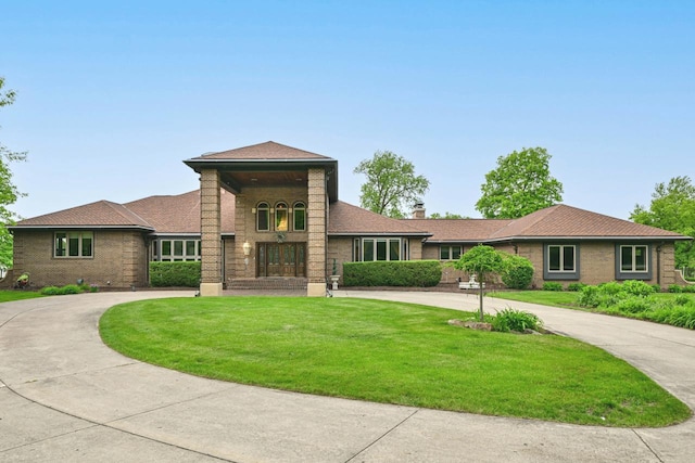 S82W15980 Bass Bay Ln, Muskego, WI 53150 - view of front of home featuring curved driveway, a front yard, brick siding, and a chimney