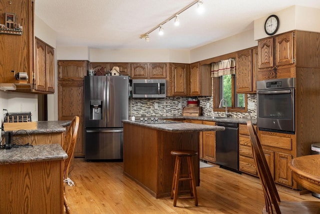 N1440 Red Oaks Dr, La Crosse, WI 54601 - kitchen featuring appliances with stainless steel finishes, dark countertops, a center island, and tasteful backsplash