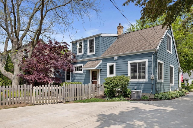415 E Willow Rd, Fox Point, WI 53217 - view of front of property with a fenced front yard, a chimney, a shingled roof, and central AC