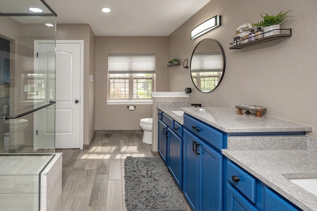 1712 Galena Dr, Port Washington, WI 53074 - bathroom featuring toilet, vanity, wood finished floors, an enclosed shower, and recessed lighting