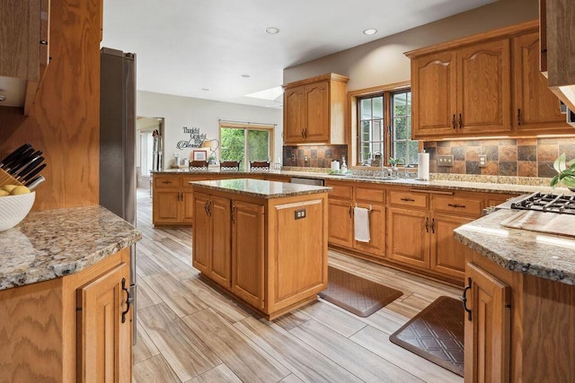 936 Broken Bow Ct, Delafield, WI 53018 - kitchen featuring a sink, backsplash, light stone countertops, a kitchen island, and recessed lighting