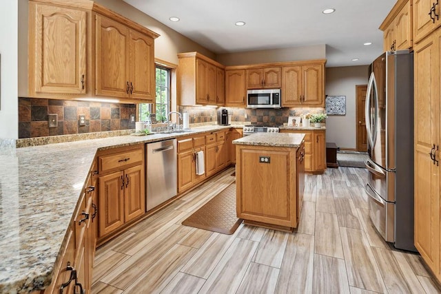 936 Broken Bow Ct, Delafield, WI 53018 - kitchen with stainless steel appliances, a center island, a sink, light stone countertops, and recessed lighting