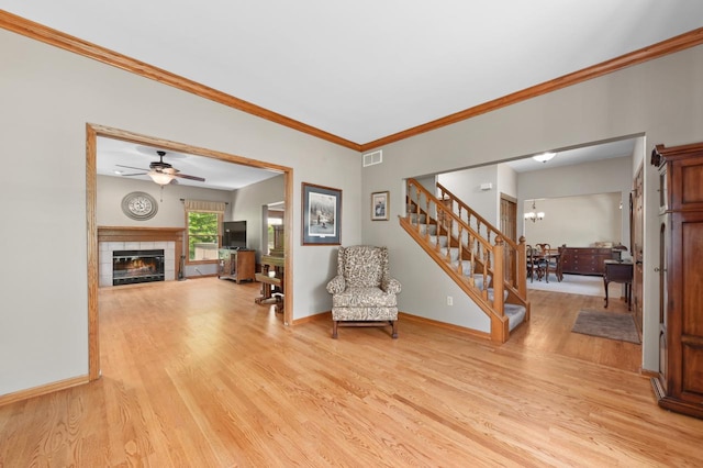 N66W13568 Crestwood Dr, Menomonee Falls, WI 53051 - living area with light wood-type flooring, ornamental molding, a fireplace, a ceiling fan, and stairway