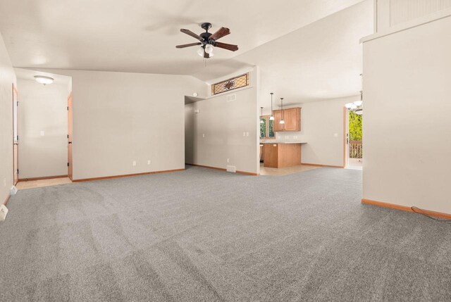 2225 Paul Rd, Manitowoc, WI 54220 - unfurnished living room with ceiling fan, baseboards, light carpet, lofted ceiling, and a chandelier
