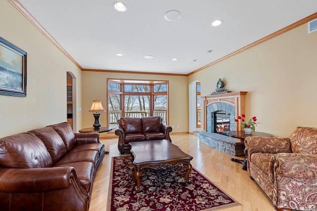 N2281 Lakewood Ln, Chilton, WI 53014 - living room with arched walkways, light wood-style flooring, a warm lit fireplace, crown molding, and recessed lighting
