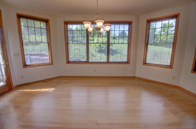 1835 Alpine Pl, Onalaska, WI 54650 - unfurnished dining area with healthy amount of natural light, a chandelier, light wood-style flooring, and baseboards
