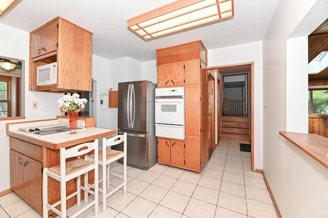 10906 W Wells St, Wauwatosa, WI 53226 - kitchen featuring white appliances, a warming drawer, light tile patterned floors, and light countertops