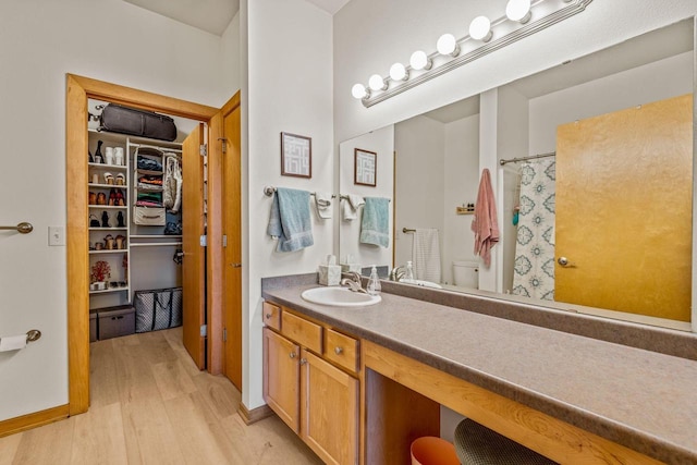 10900 W Bluemound Rd Unit 310, Wauwatosa, WI 53226 - bathroom featuring wood finished floors, vanity, toilet, curtained shower, and a walk in closet