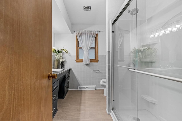 1037 S Union St, Shawano, WI 54166 - bathroom with vanity, tile walls, a stall shower, and toilet