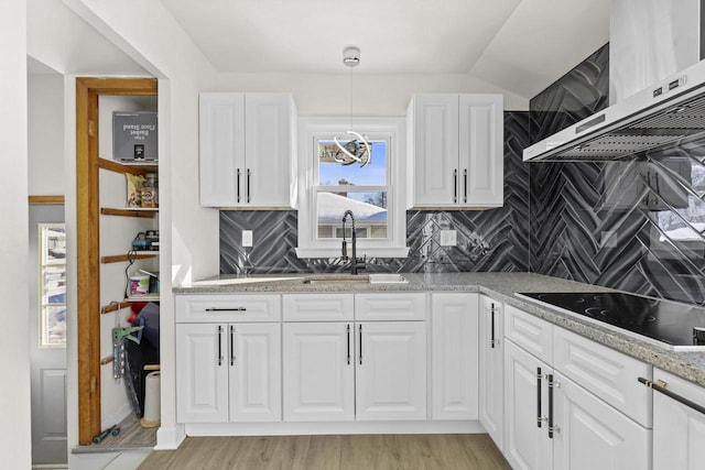 8721 W Douglas Ave, Milwaukee, WI 53225 - kitchen featuring black electric stovetop, ventilation hood, a sink, tasteful backsplash, and white cabinetry