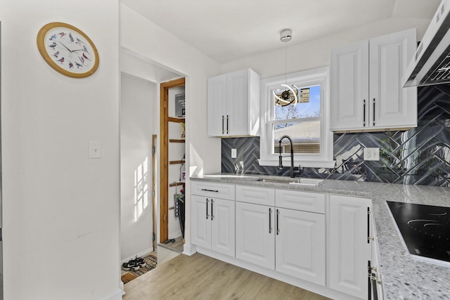 8721 W Douglas Ave, Milwaukee, WI 53225 - kitchen with a sink, black electric stovetop, exhaust hood, decorative backsplash, and white cabinetry