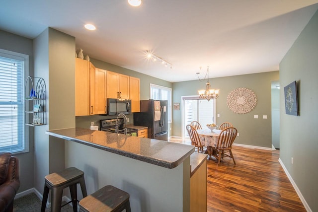 739 Shore Ln, West Bend, WI 53090 - kitchen featuring black appliances, a kitchen bar, baseboards, dark wood-style flooring, and a peninsula