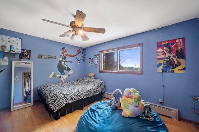 1104 Cavalier Dr, Waukesha, WI 53186 - bedroom with a baseboard heating unit, baseboard heating, wood finished floors, a ceiling fan, and baseboards