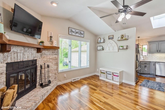2590 S 91st St, West Allis, WI 53227 - living area with a skylight, plenty of natural light, light wood-style floors, vaulted ceiling, and a fireplace