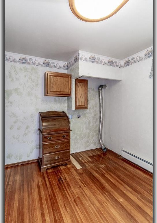 N2594 State Road 76, Hortonville, WI 54944 - unfurnished bedroom featuring baseboard heating, wood finished floors, and wallpapered walls