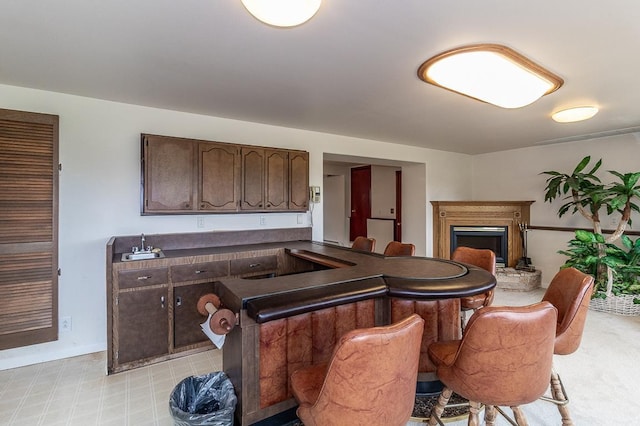 N2594 State Road 76, Hortonville, WI 54944 - kitchen with dark brown cabinetry, a breakfast bar, dark countertops, a fireplace, and baseboards