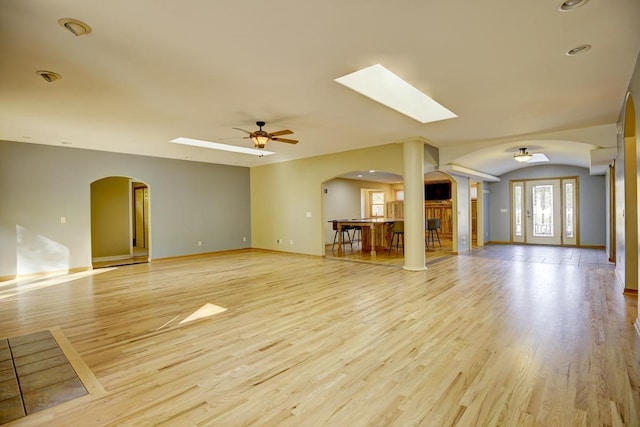 508 Frost Woods Rd, Monona, WI 53716 - unfurnished living room with a ceiling fan, a skylight, arched walkways, and light wood-style flooring