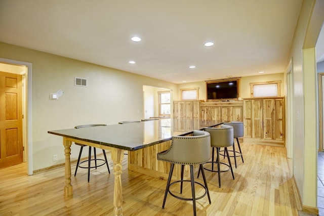 508 Frost Woods Rd, Monona, WI 53716 - kitchen with light wood-type flooring, a breakfast bar, recessed lighting, baseboards, and a large island