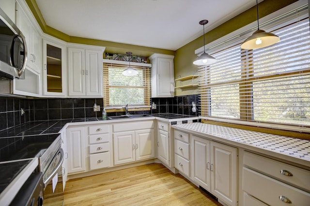 508 Frost Woods Rd, Monona, WI 53716 - kitchen with a sink, stainless steel microwave, white cabinets, hanging light fixtures, and tasteful backsplash