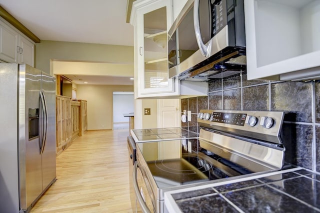 508 Frost Woods Rd, Monona, WI 53716 - kitchen with appliances with stainless steel finishes, light wood finished floors, backsplash, glass insert cabinets, and tile countertops