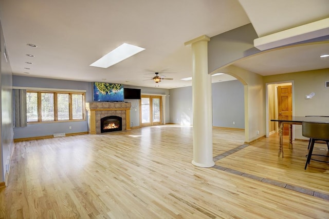 508 Frost Woods Rd, Monona, WI 53716 - unfurnished living room with wood finished floors, a fireplace, baseboards, a ceiling fan, and a skylight