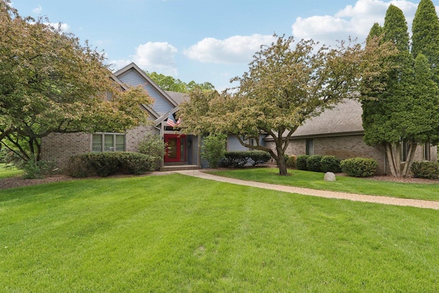 W313N4961 Chapel Ridge Rd, Hartland, WI 53029 - view of property hidden behind natural elements with a front lawn, brick siding, and a shingled roof