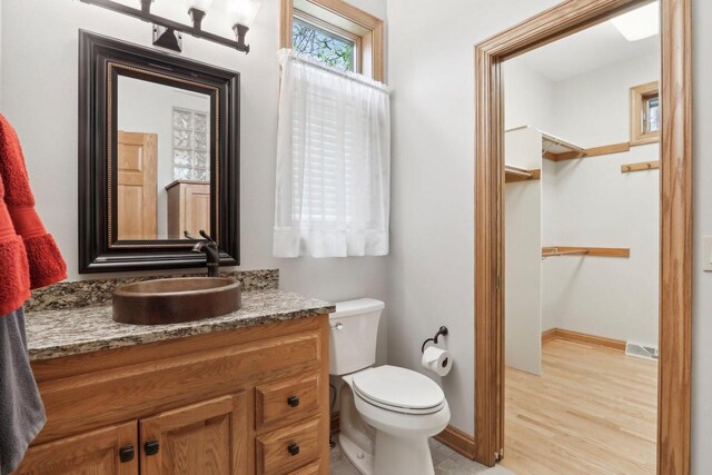 W313N4961 Chapel Ridge Rd, Hartland, WI 53029 - bathroom with vanity, toilet, wood finished floors, baseboards, and a walk in closet