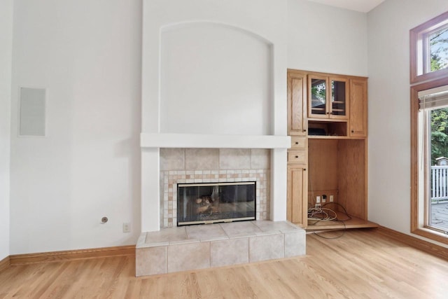 W313N4961 Chapel Ridge Rd, Hartland, WI 53029 - unfurnished living room featuring wood finished floors, a tiled fireplace, and baseboards