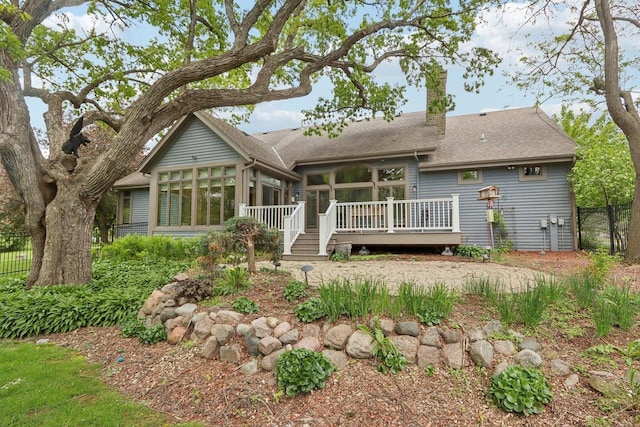 W313N4961 Chapel Ridge Rd, Hartland, WI 53029 - rear view of house featuring a sunroom, a wooden deck, a chimney, and a shingled roof