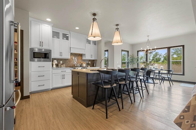 3812 Hawk Ledge Cir, De Pere, WI 54115 - kitchen featuring appliances with stainless steel finishes, light wood-style flooring, a kitchen island with sink, tasteful backsplash, and recessed lighting