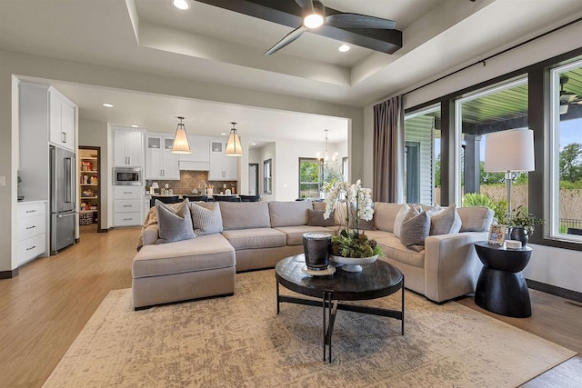 3812 Hawk Ledge Cir, De Pere, WI 54115 - living room with light wood-style floors, a chandelier, a ceiling fan, recessed lighting, and a raised ceiling