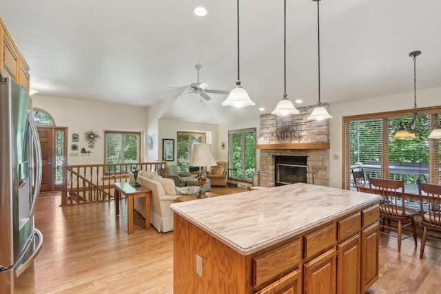 16625 Tanglewood Dr, Brookfield, WI 53005 - kitchen featuring stainless steel fridge with ice dispenser, ceiling fan, a stone fireplace, a kitchen island, and light wood finished floors