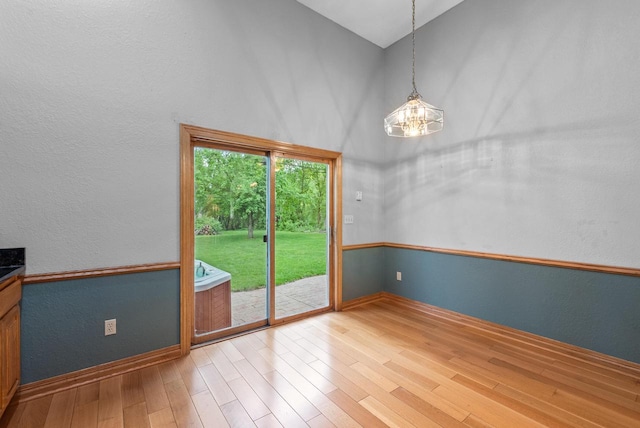6241 N 118th St, Milwaukee, WI 53225 - unfurnished dining area with a high ceiling, baseboards, wood finished floors, a textured wall, and a chandelier