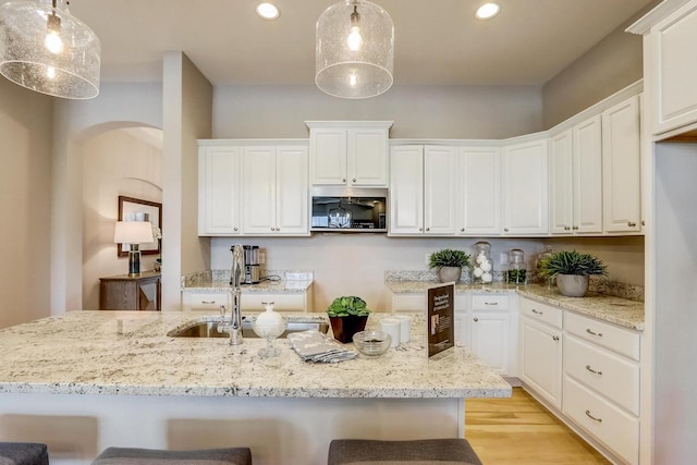 1626 Belmont Ln Unit 27, Oconomowoc, WI 53066 - kitchen featuring arched walkways, white cabinetry, recessed lighting, a breakfast bar area, and light wood-style flooring