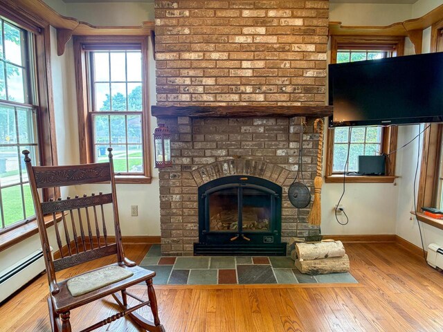 315 Lampert St, Oshkosh, WI 54901 - living area with baseboards, wood finished floors, a brick fireplace, and baseboard heating