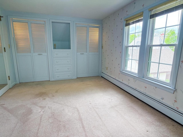 315 Lampert St, Oshkosh, WI 54901 - unfurnished bedroom with baseboard heating, multiple closets, light colored carpet, and wallpapered walls