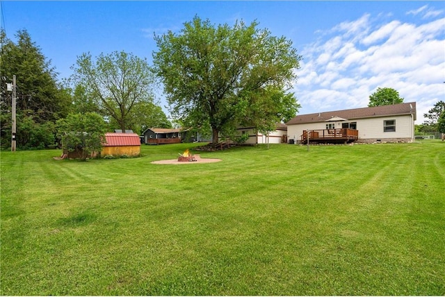 505 Lake Ave, Frederic, WI 54837 - view of green lawn featuring a wooden deck and an outdoor fire pit