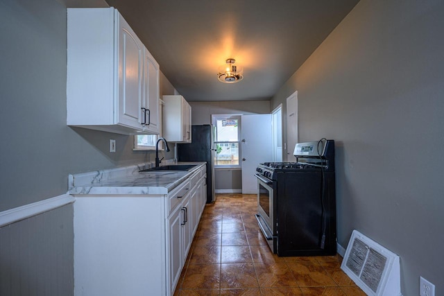 3776 S 16th St, Milwaukee, WI 53221 - kitchen with stainless steel gas range, a sink, white cabinetry, light countertops, and tile patterned floors