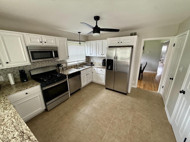219 W Daphne St, Milwaukee, WI 53217 - kitchen with appliances with stainless steel finishes, decorative backsplash, white cabinetry, a sink, and light stone counters