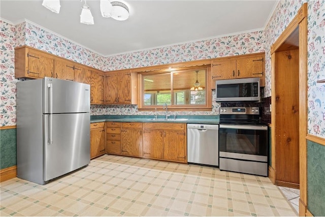 632 E 2nd St, New Richmond, WI 54017 - kitchen featuring stainless steel appliances, wallpapered walls, brown cabinets, ornamental molding, and light floors