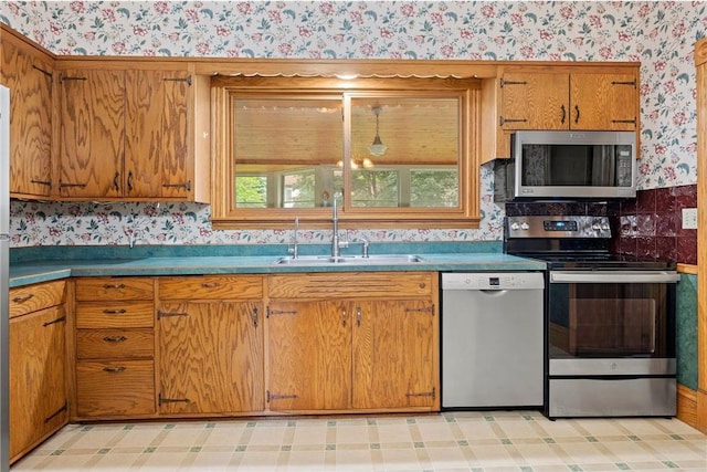 632 E 2nd St, New Richmond, WI 54017 - kitchen with stainless steel appliances, wallpapered walls, brown cabinets, and light floors