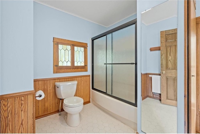 632 E 2nd St, New Richmond, WI 54017 - bathroom with a wainscoted wall, radiator, wooden walls, ornamental molding, and bath / shower combo with glass door