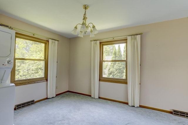 4705 Agate Ln, Madison, WI 53714 - unfurnished room featuring stacked washer / dryer, a chandelier, light colored carpet, and baseboards