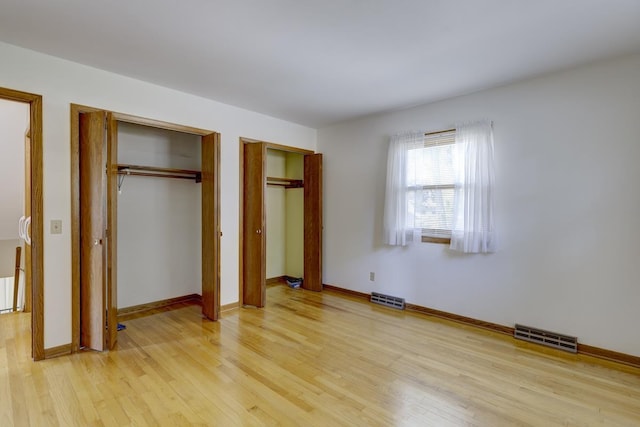4705 Agate Ln, Madison, WI 53714 - unfurnished bedroom featuring two closets, light wood-style flooring, and baseboards