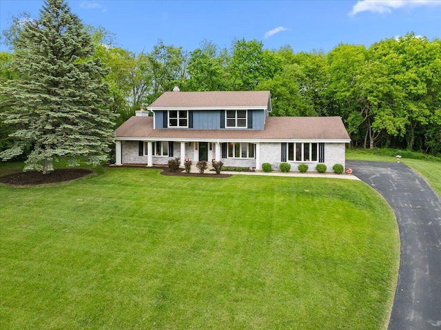 W308N5583 Windrise Cir, Hartland, WI 53029 - traditional-style home featuring a front yard, covered porch, asphalt driveway, and a chimney