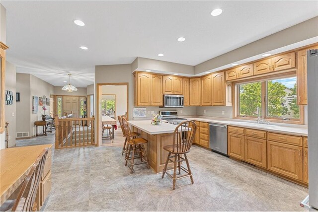 1115 S Trappers Xing, Hugo, MN 55038 - kitchen with stainless steel appliances, a sink, a kitchen bar, light countertops, and recessed lighting