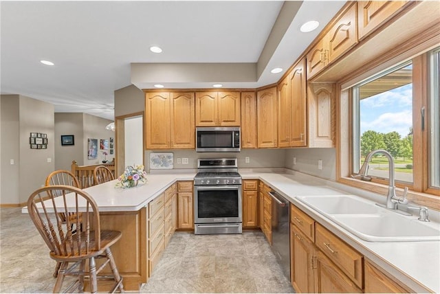 1115 S Trappers Xing, Hugo, MN 55038 - kitchen featuring appliances with stainless steel finishes, a sink, a peninsula, a kitchen breakfast bar, and light countertops