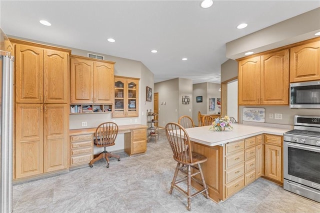 1115 S Trappers Xing, Hugo, MN 55038 - kitchen featuring appliances with stainless steel finishes, a peninsula, a kitchen bar, light countertops, and glass insert cabinets